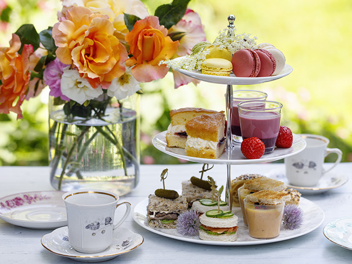 A table set up for afternoon tea with three tiers of sandwiches and cakes