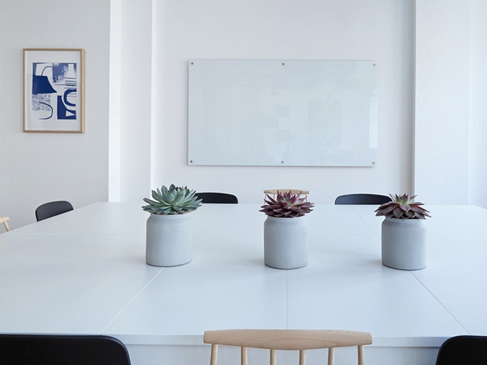 A white table with three vases with plants