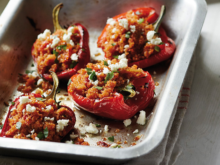 Four smoky quinoa stuffed peppers in a roasting tin